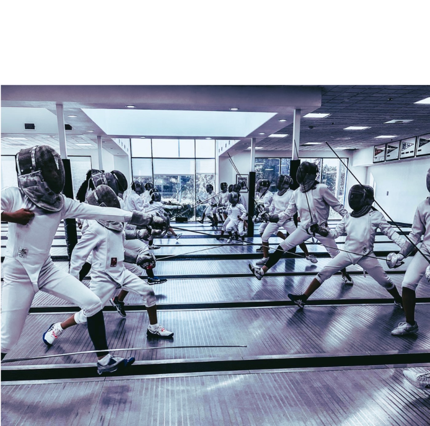 Children and adults practicing fencing in the PFA training room